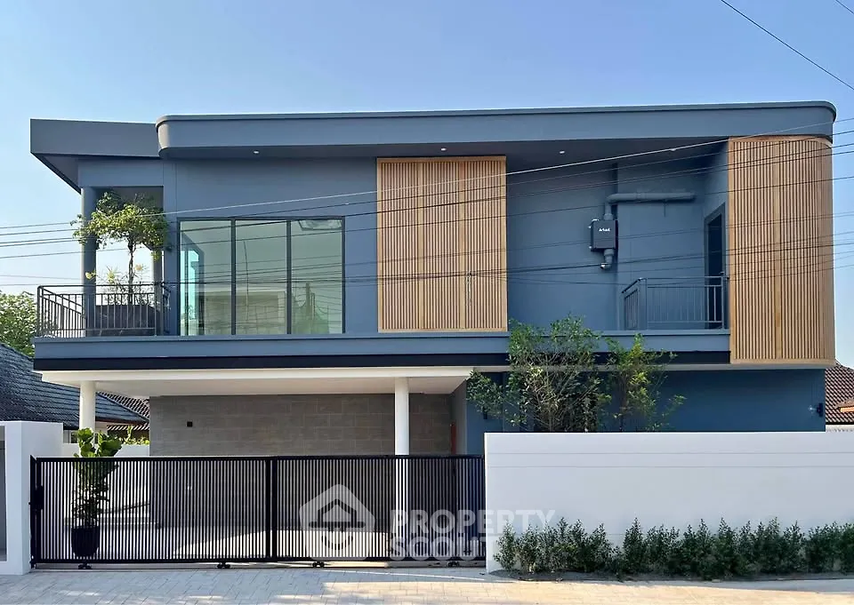 Modern two-story house with sleek design and large windows, featuring a spacious balcony and stylish facade.
