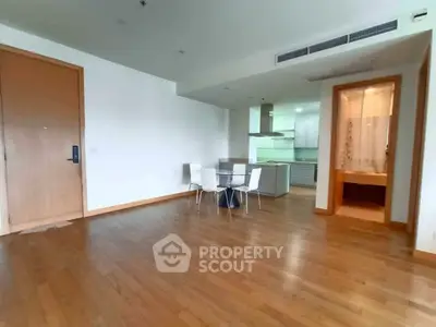 Spacious open-plan living area with modern kitchen and dining space, featuring wooden flooring and ample natural light.