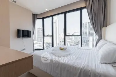 Modern bedroom with city view and large windows in high-rise apartment.