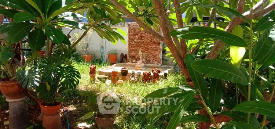Lush garden with decorative fountain and potted plants in serene backyard setting.