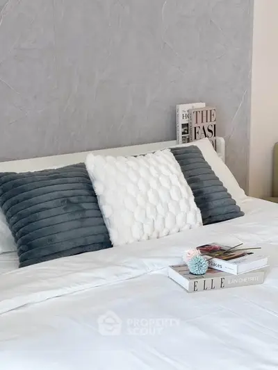 Elegant bedroom with plush pillows and stylish decor magazines on bed.