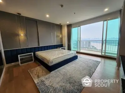 Spacious bedroom with large windows offering a panoramic view, elegant lighting, and a plush king-sized bed, leading to a private balcony.