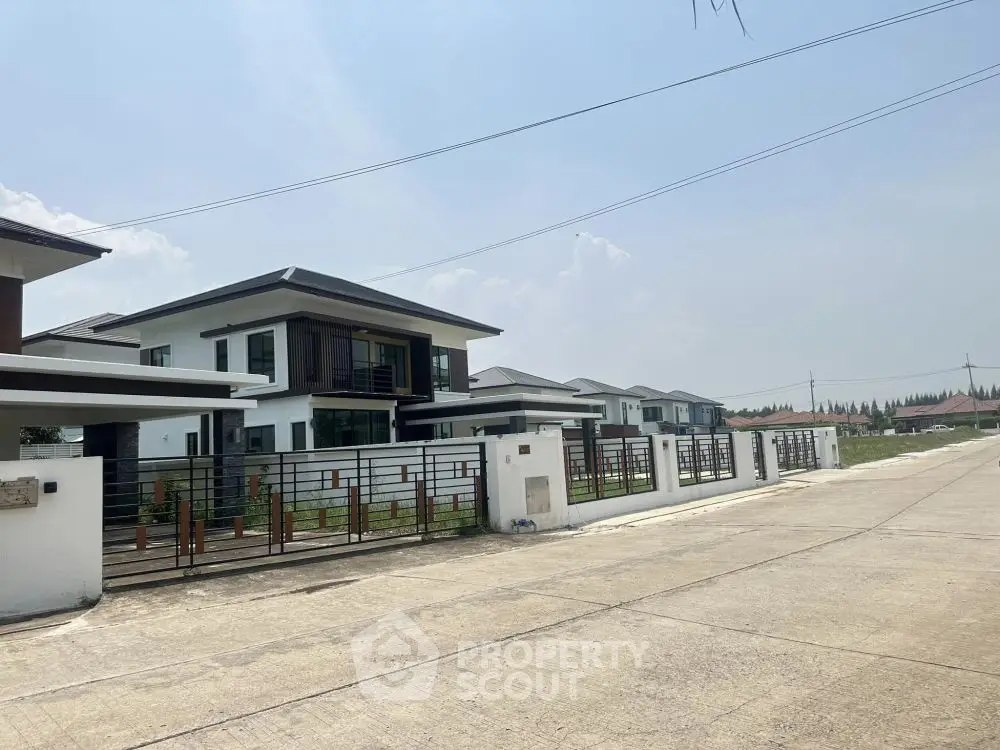 Modern suburban homes with sleek design and spacious driveways under a clear sky.