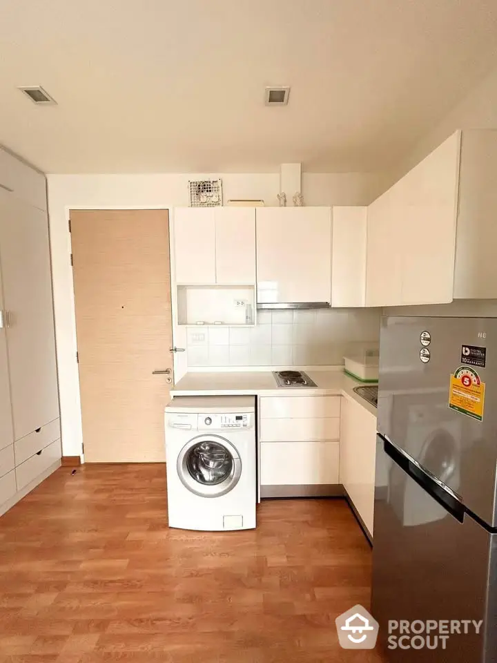 Modern kitchen with washing machine and fridge in compact layout