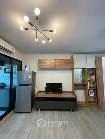 Modern living room with stylish lighting and sleek furniture, featuring a fridge and TV unit.