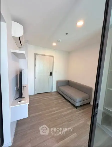 Modern living room with sleek gray sofa and wall-mounted TV in a stylish apartment.