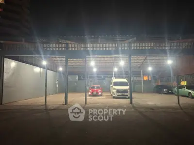 Spacious parking area with multiple vehicles under bright lights at night.