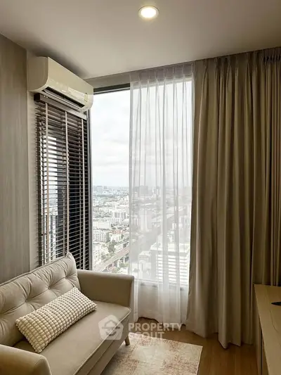 Modern living room with city view, featuring a cozy sofa and large window with sheer curtains.