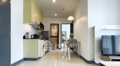 Modern open-plan living room with kitchen and dining area, featuring sleek appliances and stylish decor.