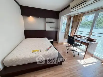 Modern bedroom with large windows, wooden flooring, and a study desk, perfect for natural light lovers.