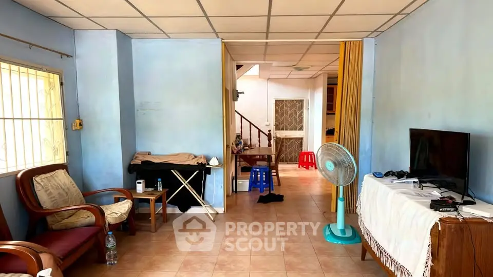 Spacious living room with tiled floor, cozy seating, and natural light, perfect for relaxation and entertainment.