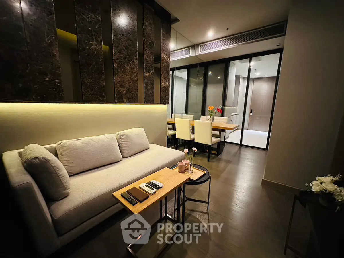 Modern living room with elegant decor and open dining area, featuring sleek furniture and ambient lighting.