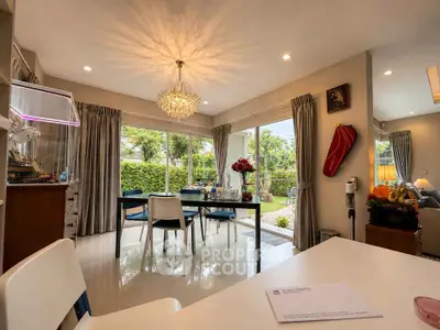Elegant living room with chandelier, large windows, and garden view, perfect for modern family living.