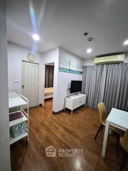 Modern living room with wooden flooring, TV, and dining area in a cozy apartment.