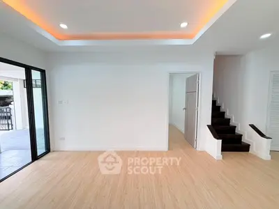 Spacious modern living room with wooden flooring and recessed lighting, featuring an open layout and staircase.