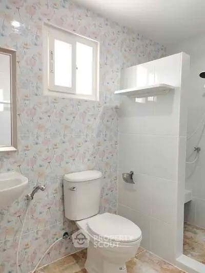 Charming bathroom with floral tiles and modern fixtures, perfect for a cozy home.