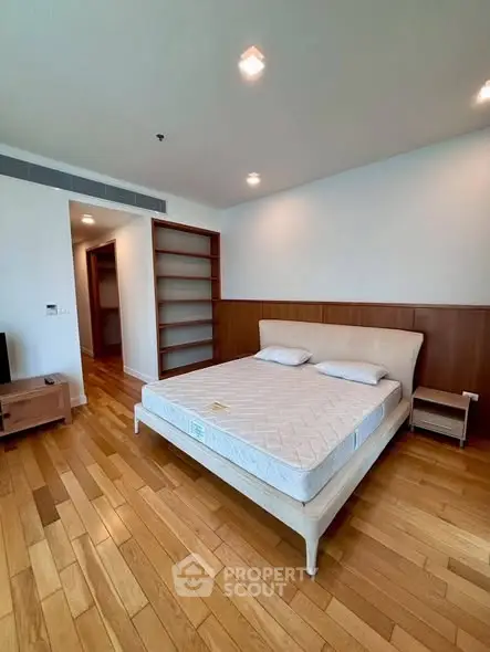 Spacious bedroom with wooden flooring and modern furnishings in a luxury apartment.