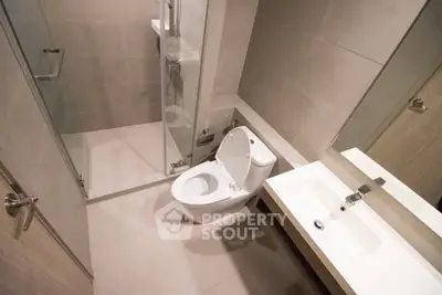 Modern bathroom with sleek fixtures and glass shower enclosure in a contemporary apartment.