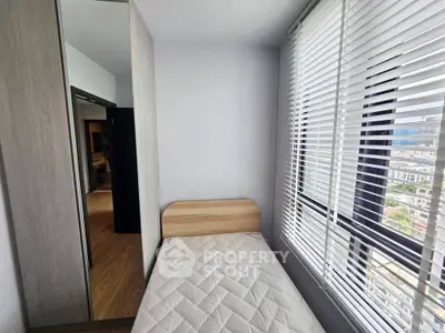 Cozy bedroom with city view, featuring a single bed and large window with blinds.