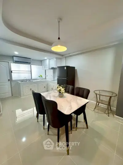 Modern kitchen with dining area featuring sleek black chairs and marble table, bright and spacious layout.