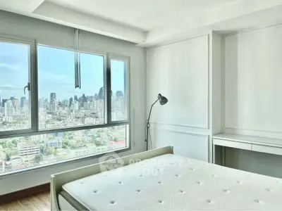 Bright bedroom with city view, featuring large window and minimalist decor.