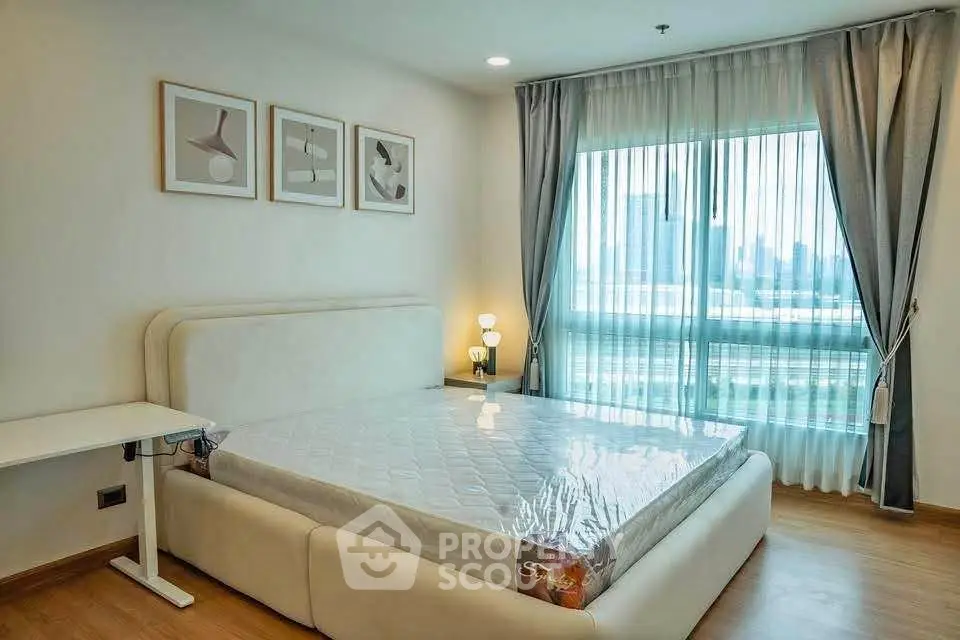 Modern bedroom with large window and stylish decor in a high-rise apartment.