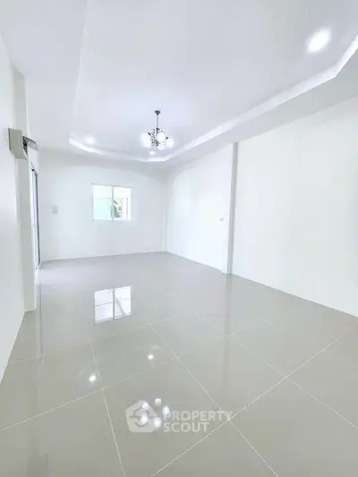 Spacious empty room with glossy tiled floor and modern chandelier