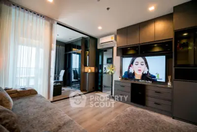 Modern living room with stylish decor and open layout, featuring a large TV and cozy seating area.