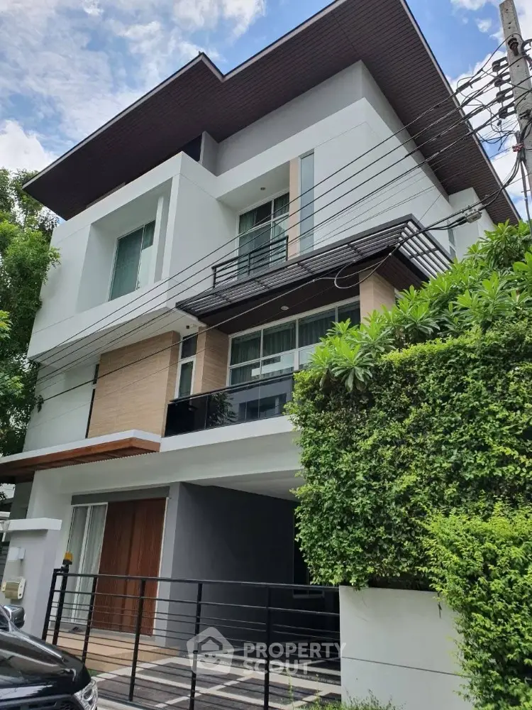 Modern multi-story house with sleek design and lush greenery