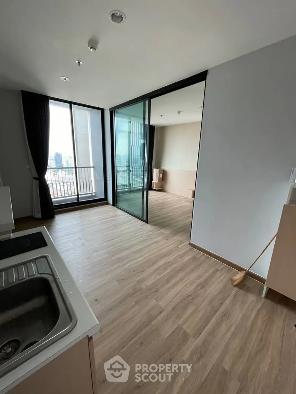 Modern apartment with open layout and city view from balcony, featuring sleek flooring and large windows.