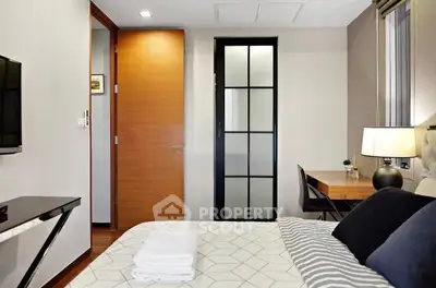 Modern bedroom with stylish decor and workspace, featuring a cozy bed and sleek furniture.