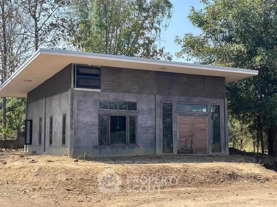 Modern minimalist house with large windows and flat roof in a serene natural setting.