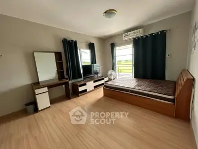 Spacious bedroom with modern furnishings and large windows for natural light.