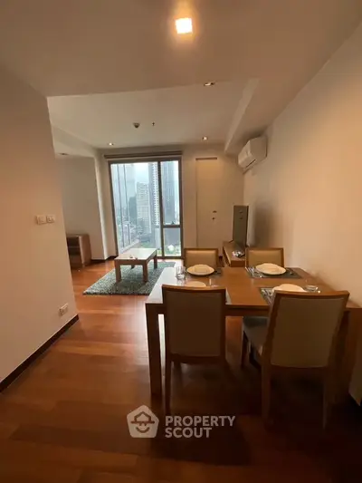 Modern living room with dining area and city view, featuring wooden flooring and stylish furniture.