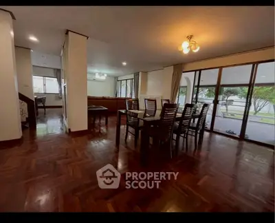 Spacious dining area with elegant wooden flooring and large windows offering garden views.