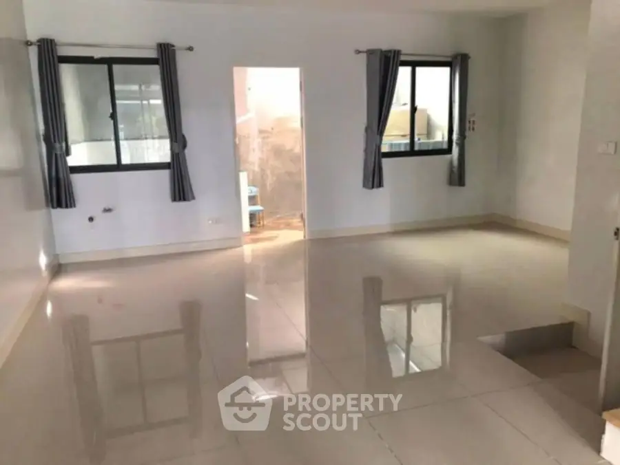 Spacious empty room with tiled flooring and large windows, ready for customization.