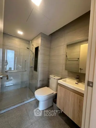 Modern bathroom with glass shower and sleek fixtures in contemporary apartment.