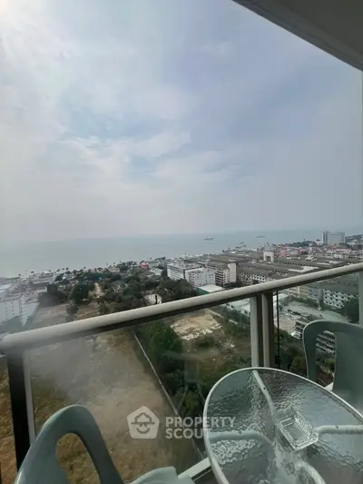 Stunning ocean view from high-rise balcony with glass table and chairs
