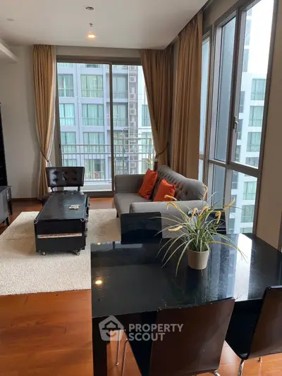 Modern living room with large windows and stylish furniture in a high-rise apartment.