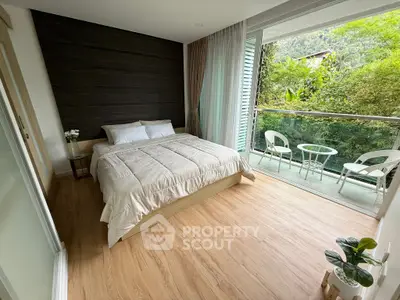 Spacious bedroom with balcony and lush garden view, featuring modern decor and cozy ambiance.