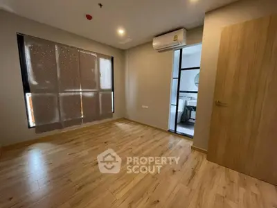 Spacious bedroom with wooden flooring and modern air conditioning unit