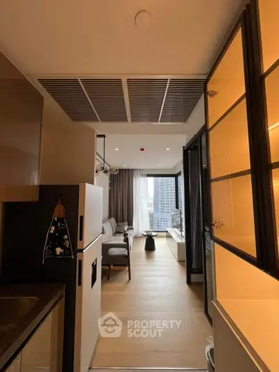 Modern apartment interior with open kitchen and spacious living area, featuring large windows and city view.