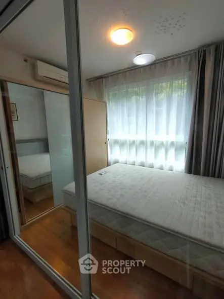 Cozy bedroom with large window and mirrored wardrobe, perfect for natural light lovers.