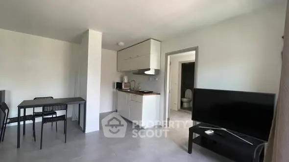 Modern open-plan living room with sleek kitchen and dining area, featuring contemporary furniture and neutral tones.