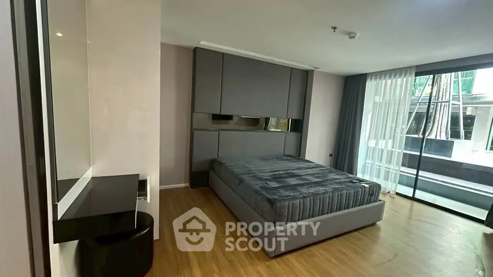 Modern bedroom with sleek design and large window offering natural light