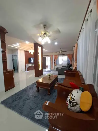 Spacious living room with elegant wooden furniture and plush rug, perfect for family gatherings.
