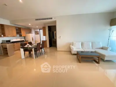 Spacious open-plan living room with modern kitchen and dining area, featuring sleek furniture and ample natural light.