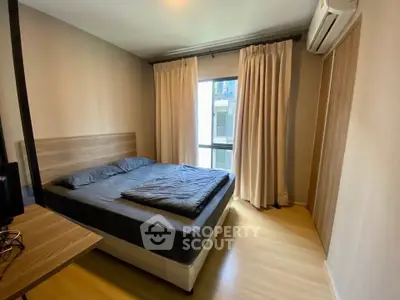 Modern bedroom with wooden flooring and large window for natural light