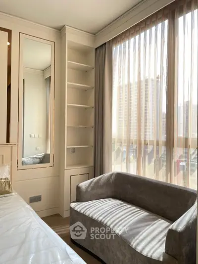 Bright bedroom with large window, elegant sofa, and built-in shelves in modern apartment.