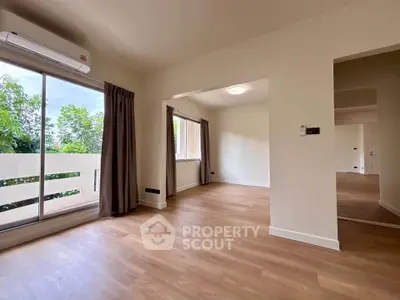 Spacious living room with wooden flooring and large windows for natural light.